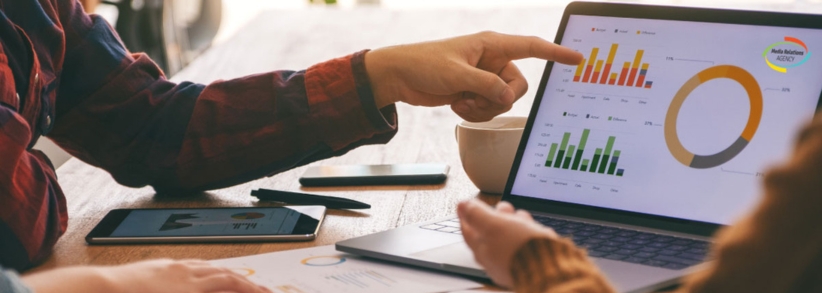 Hands pointing at laptop screen with graphs on screen