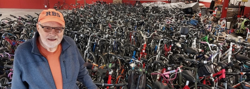 Rick's Bike Sale for Kids N Kinship. Man in front of hundreds of bikes